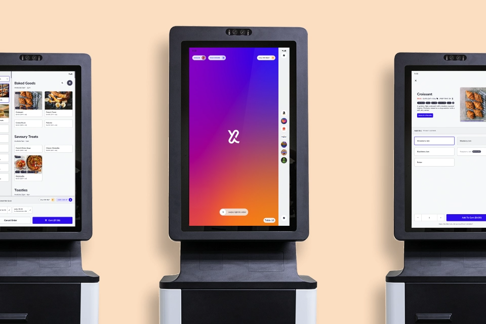 Three self-service kiosks showing ordering screens